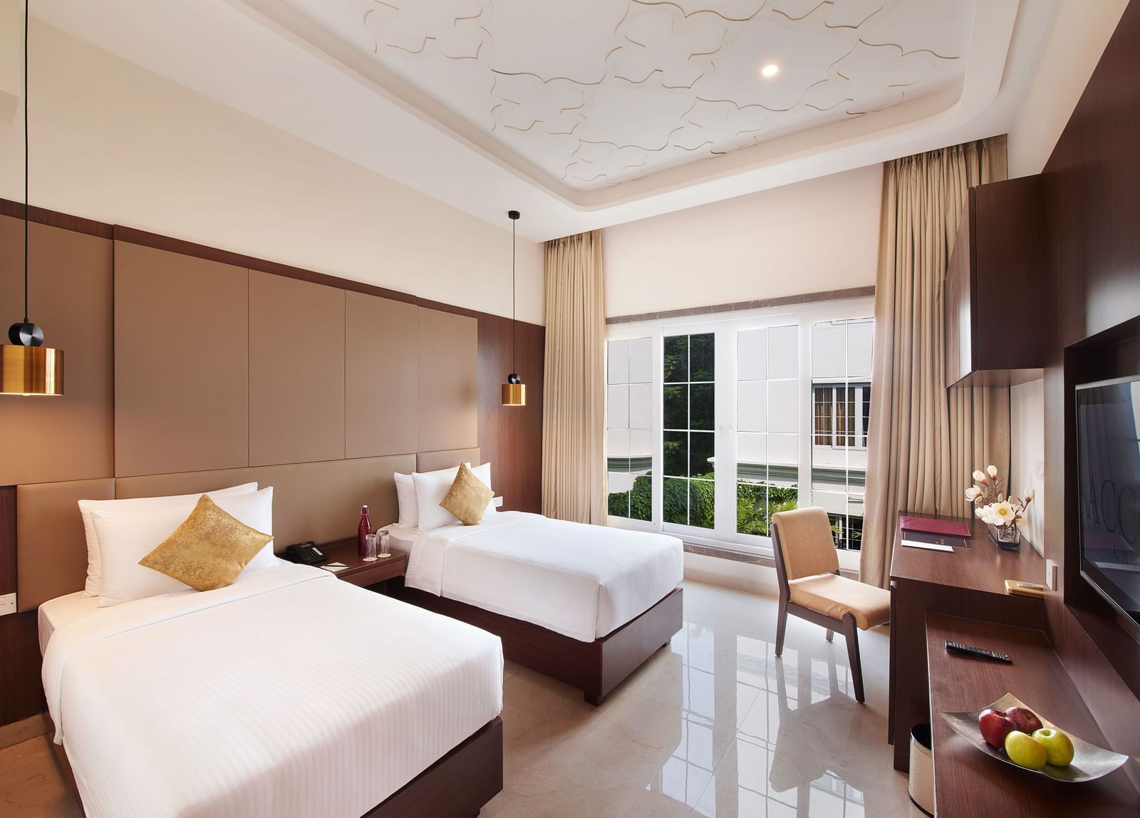 A room in Chromepet with double beds, a work desk with a chair, and hanging lamps - Accord Chrome Airport Hotel